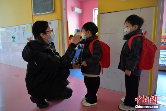 资料图:河北石家庄市某幼儿园,老师为小朋友测量体温.