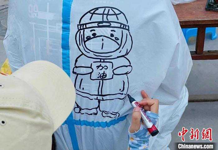 许艳星在医护人员做核酸监测休息的间隙，为医护人员手绘防护服。　赵路沙 摄