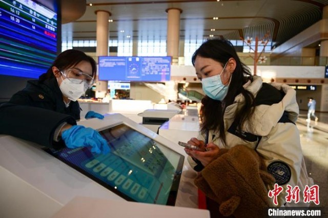 图为王晓楠(左)在服务台为旅客查询车次。　于海洋 摄