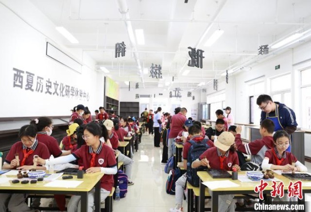 银川景博学校的学生们在宁夏西夏王陵景区体验西夏文木活字印刷术。　于晶 摄