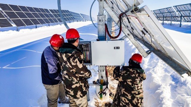 华能聚宝光伏电站巡检人员在对光伏组件进行检修，确保设备安全稳定运行。翁雪尘摄