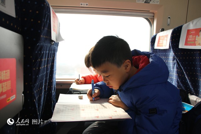 1月25日，西安北开往深圳北的G828次列车上，两位小朋友正在写寒假作业。人民网记者 贾凯璐摄