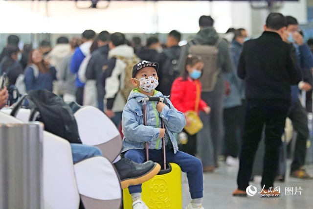 2024年1月25日，厦门北站候车室里的一位小乘客坐在行李箱上东张西望，等待着回家的列车。人民网记者 陈博摄