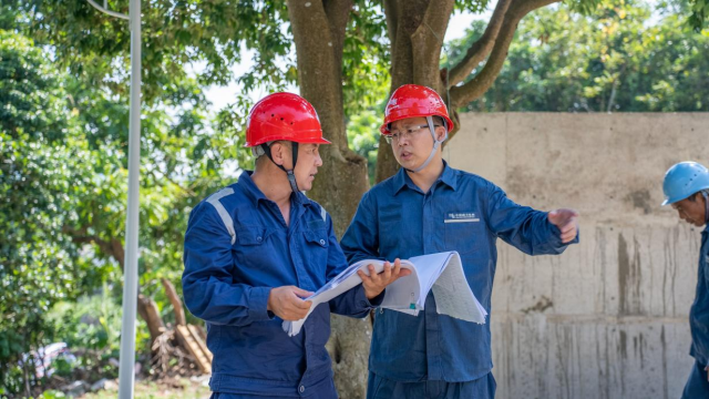 叶林青和施工人员在施工现场协调项目建设问题。广东电网公司供图