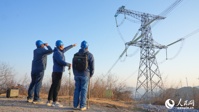 江西送变电公司输电运检分公司九江巡检站检修人员正在通过望远镜查看塔基及导线附近有无障碍物。人民网 孔文进摄