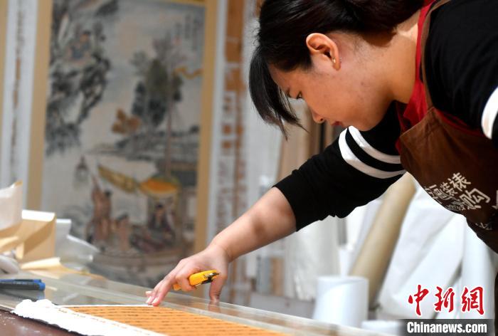 图为：陈雨正在裁边。　吕明 摄