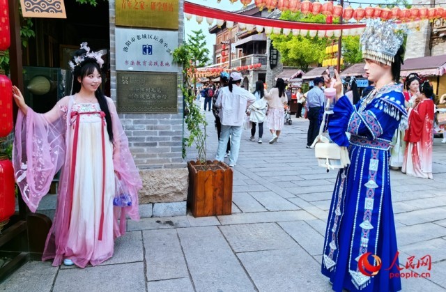 穿上汉服，游客在位于洛阳市老城区的洛邑古城拍照留念。人民网记者 王佩摄