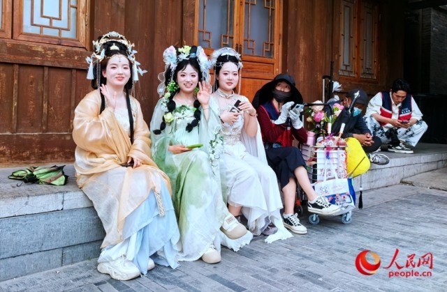 在河南省洛阳市洛邑古城内，几位汉服小姐姐趁拍照打卡间隙休息。人民网记者 王佩摄